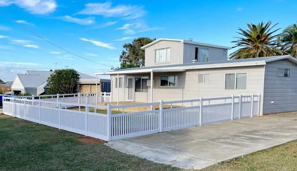 White Hamptons-style PVC fencing around a coastal home